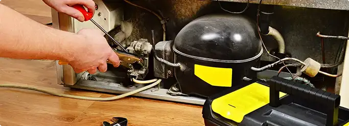 Refrigerator repair technician fixing the compressor and wiring in Pueblo, CO